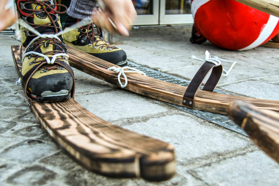 Schuhe werden auf historische Holzski geschnürt