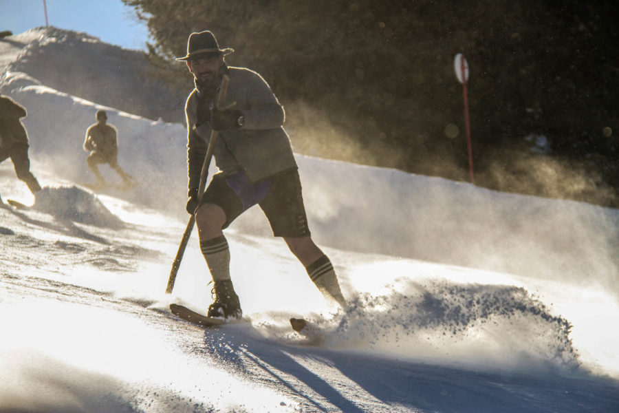 Ein Mann fährt auf der Skipiste mit historischen Holzski