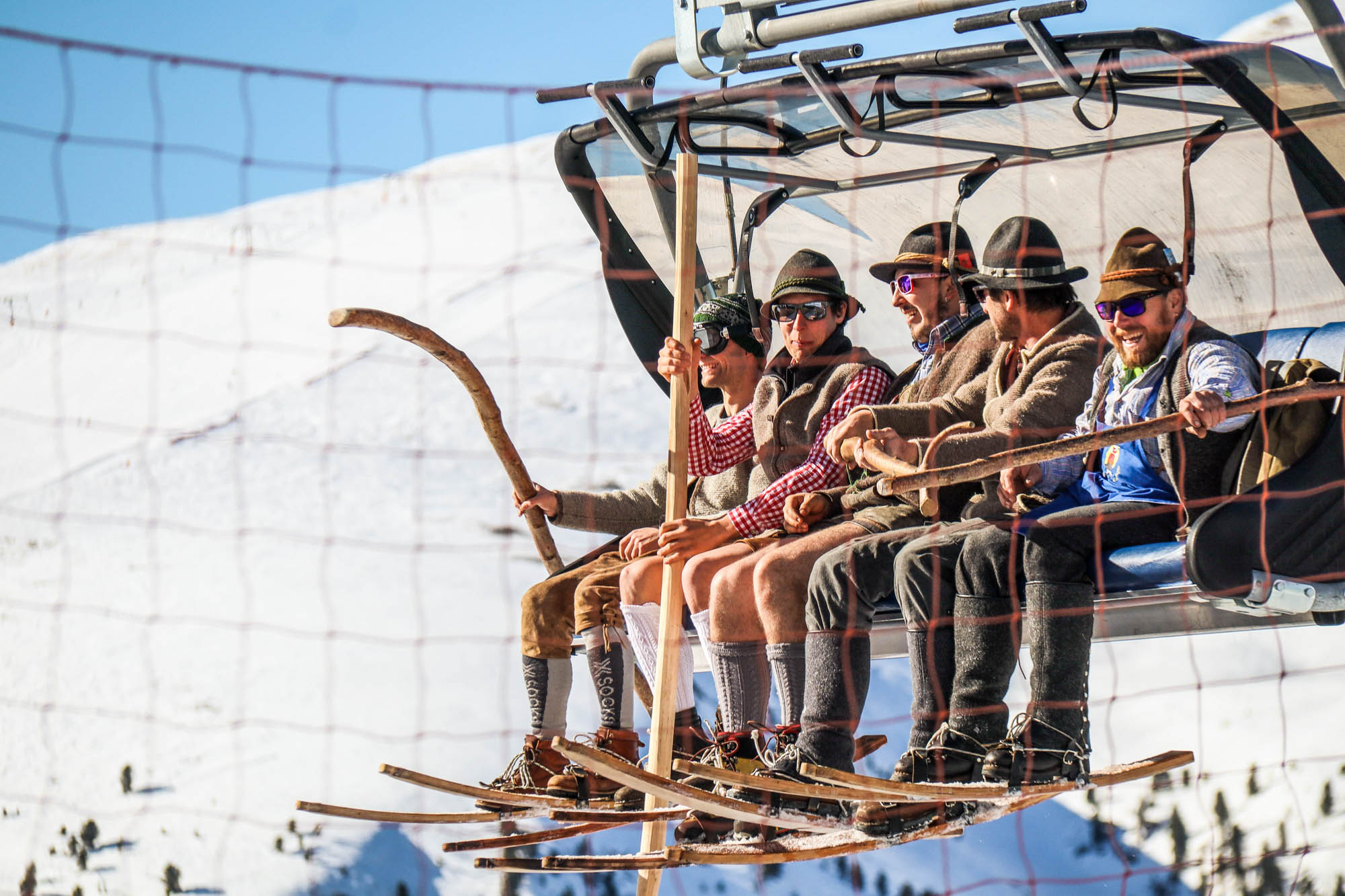 Fünf Männer in Tracht und mit historischen Ski im Sessellift