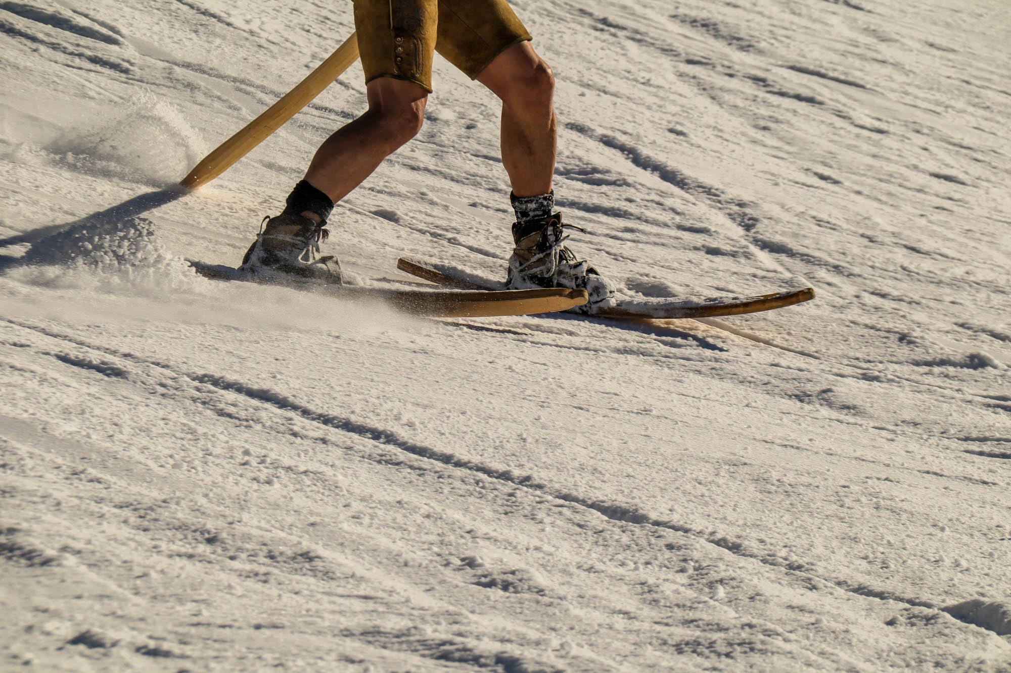 Ein Mann fährt auf der Skipiste mit historischen Holzski