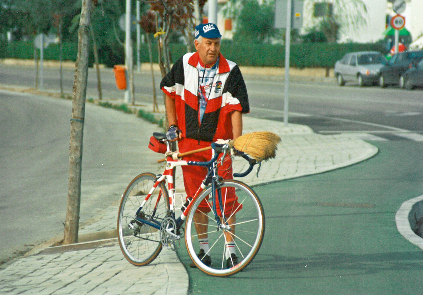 Ein Mann steht mit einem Besen hinter seinem Fahrrad