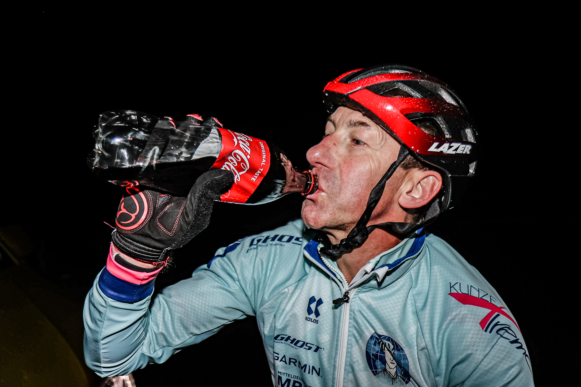 Extremsportler Guido Kunze nimmt nachts einen Schluck aus einer Cola-Flasche